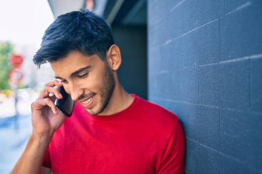 Genç Latin adam gülümsüyor. Şehirdeki akıllı telefondan konuşuyor..