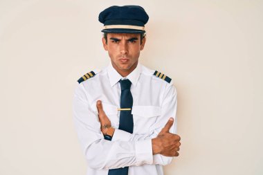 Uçak pilotu üniforması giyen genç İspanyol adam şüpheci ve gergin, yüzünde çapraz kollu tasvip etmeyen ifade. negatif kişi. 