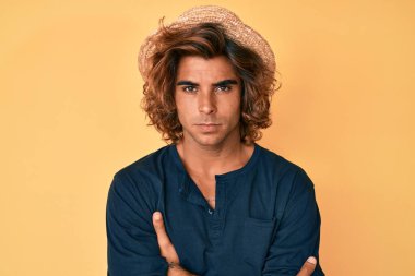 Yazlık şapkalı, kuşkucu ve gergin genç İspanyol bir adam. Yüzünde çapraz kollu tasvip etmeyen bir ifade var. negatif kişi. 