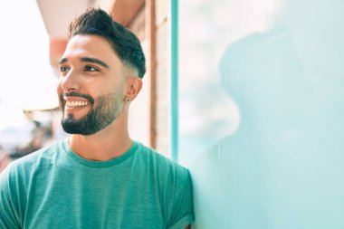 Genç Arap adam gülümsüyor. Şehrin duvarına yaslanmış mutlu..