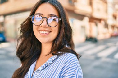 Genç İspanyol iş kadını şehirde mutlu bir şekilde yürürken gülümsüyor.