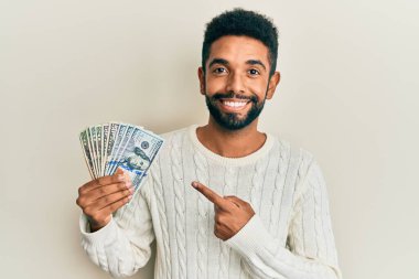 Yakışıklı, sakallı, dolarlar tutan, mutlu, eli ve parmağı olan bir adam. 