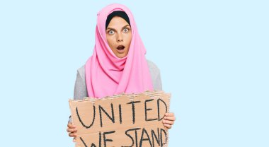 Kafkasyalı genç bir kadın birarada duruyor pankartımız korkmuş ve hayrete düşmüş bir şekilde şaşkınlık içinde şaşkınlık içinde, inançsız bir yüz ifadesi takınıyoruz. 