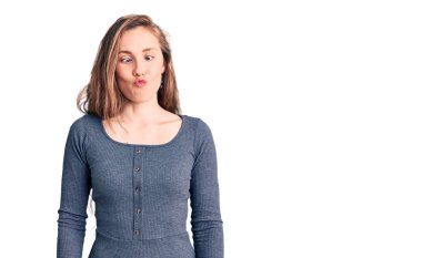 Genç, güzel, sarışın, sıradan bir elbise giymiş dudaklarıyla balık suratı yapan, çılgın ve komik bir jest yapan bir kadın. Komik ifade. 