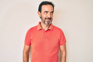 Orta yaşlı, sıradan kıyafetler giyen, gülümseyen, yan bakıp düşünen İspanyol bir adam.. 