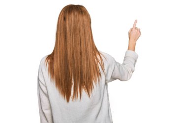 Kış süveteri giyen genç İrlandalı kadın, parmak eliyle öne doğru poz veriyor. 