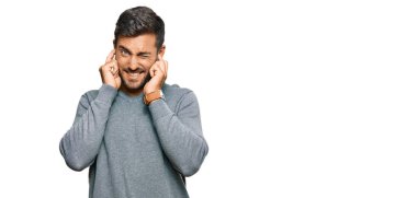 Gürültülü müzik sesi için günlük kıyafetler giyen, kulaklarını parmaklarıyla kapatan yakışıklı İspanyol bir adam. sağır kavramı. 