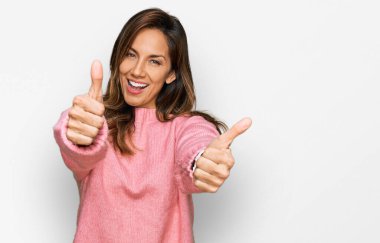 Latin kökenli genç bir kadın, günlük giysiler giyip, olumlu jestler yapıyor, gülümsüyor ve başarı için seviniyor. kazanan jest. 