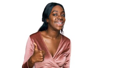 Genç Afro-Amerikan kadın seksi parti elbisesi giyip mutlu bir el hareketi yapıyor. Kameraya bakıp başarıyı gösteren ifade. 