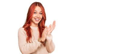 Genç kızıl saçlı kadın, sıradan bir kazak giyiyor, alkışlıyor, alkışlıyor, mutlu ve mutlu, gururlu elleri bir arada. 