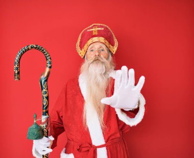 Geleneksel Aziz Nicholas kostümü giyen gri saçlı ve uzun sakallı yaşlı bir adam avucunun içi gibi şarkı söylemeyi kesiyor. Yüzünde olumsuz ve ciddi bir jest olan uyarı ifadesi. 