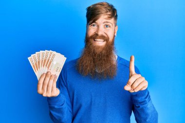 5000 Güney Koreli 'yi elinde tutan genç İrlandalı kızıl adam bir fikir veya soru işareti ile gülümseyen bir banknot kazandı. 