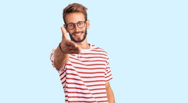 Sakallı, sıradan kıyafetler ve gözlük takan yakışıklı sarışın adam selamlaşma ve dostça el sıkışma hediyesi olarak gülümsüyor. başarılı iş. 