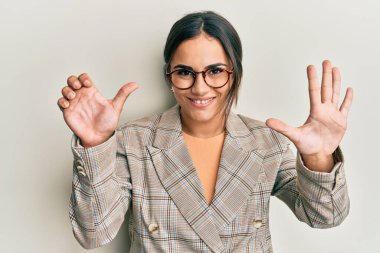 Young brunette woman wearing business jacket and glasses showing and pointing up with fingers number six while smiling confident and happy. 