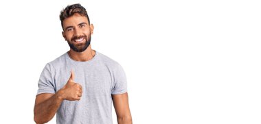 Gündelik kıyafetler giyen genç İspanyol adam elleriyle mutlu bir jest yapıyor. Kameraya bakıp başarıyı gösteren ifade. 