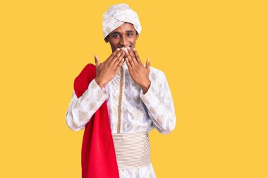 Gelenek giyinmiş Afrikalı yakışıklı bir adam Sherwani sari elbisesi giyiyor. Gülüyor ve utanıyor. Ağzı ellerle, dedikoduyla ve skandal konseptiyle örtüyor. 