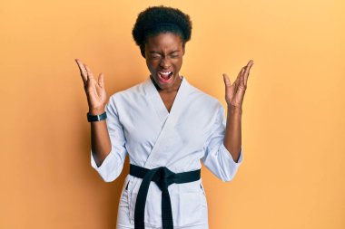 Karate kimonosu ve siyah kuşak giyen Afrikalı genç bir kız başarının çılgınlığını kollarını kaldırmış ve gözlerini kapatmış heyecanla haykırarak kutluyor. Kazanan konsept 