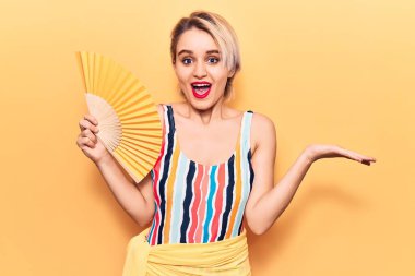 Mayo giyen genç, sarışın bir kadın el ele tutuşup başarıyı mutlu bir gülümsemeyle ve elini kaldırarak kutluyor. 