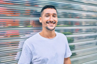 Genç İspanyol adam gülümsüyor mutlu bir şekilde şehrin duvarına yaslanıyor..