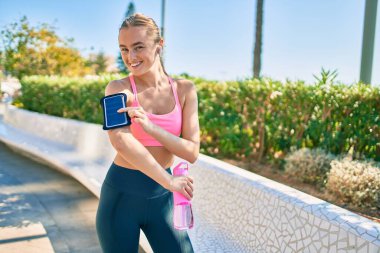 Genç sarışın sporcu şehirde bir şişe su içerek egzersiz yapıyor.