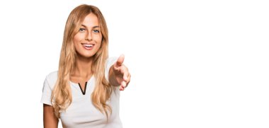 Güzel sarışın genç bayan, günlük beyaz tişört giyip gülümseyerek dostça tokalaşıyor ve hoş geldin diyor. başarılı iş. 