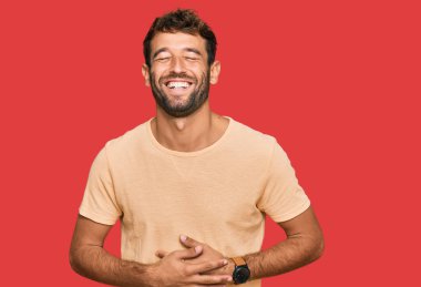 Yakışıklı, sakallı, sıradan tişörtlü, gülen ve kahkahalarla gülen bir delikanlı.. 