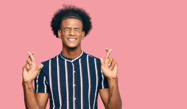 Afro saçlı, sıradan giyinmiş, umut ve gözlerin kapalı bir şekilde gülümseyerek el hareketi yapan Afro-Amerikan bir adam. Şans ve batıl inançlar. 