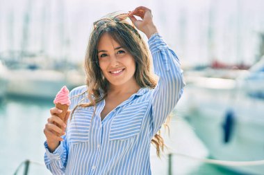 Genç İspanyol kadın gülümseyerek limanda dondurma yiyor..