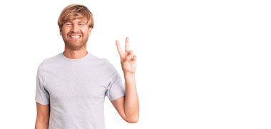 Sakallı, sıradan tişörtlü, neşeli yüzüyle kameraya gülümseyen yakışıklı beyaz adam zafer işareti yapıyor. İki numara.. 