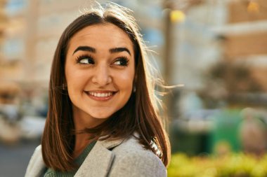 Genç İspanyol kız gülümseyerek şehirde mutlu mesut dikiliyor..