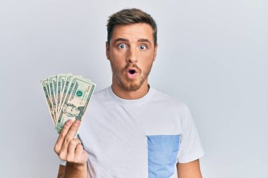 Yakışıklı beyaz adam elinde 20 dolarlık banknot tutuyor. Şaşırmak için ağzı açık kalmış, korkmuş ve hayrete düşmüş. İnanmayan yüz. 