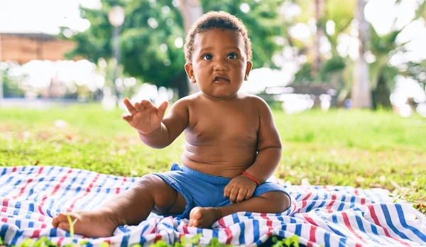 公園で草の上に座っている愛らしいアフリカ系アメリカ人の幼児 — ストック写真