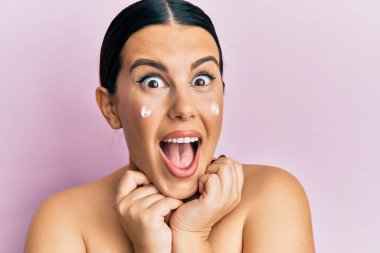 Güzel esmer kadın, üstsüz, yüz kremi sürmüş. Çılgınca kutlama yapıyor ve başarı için hayrete düşüyor. Gözleri açık, heyecanlı çığlıklar atıyor.. 