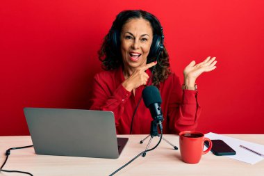 Radyo stüdyosunda çalışan orta yaşlı güzel bir kadın kameraya hayret ediyor ve gülümsüyor.. 