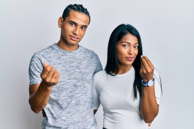 Genç Latin çift gündelik kıyafetler giyip İtalyan jesti yapıyorlar. Elleri ve parmakları ile kendinden emin ifade ediyorlar. 