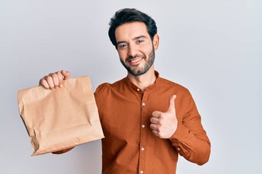İspanyol asıllı genç adam elinde güler yüzlü, mutlu ve olumlu bir gülümsemeyle yiyecekleri alıp götürüyor, başparmağıyla mükemmel ve onay işareti yapıyor. 