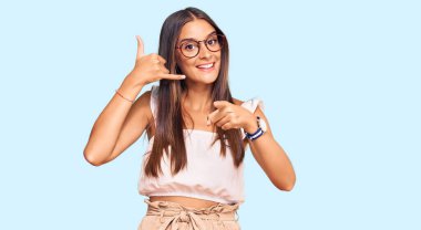 Günlük kıyafetler ve gözlük takan genç İspanyol kadın gülümsüyor telefonda konuşuyor ve seni işaret ediyor. Ara beni.. 