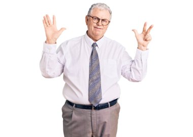 Yaşlı, gri saçlı, iş kıyafetleri giyen, 8 numaralı parmaklarıyla işaret eden, kendinden emin ve mutlu bir adam.. 