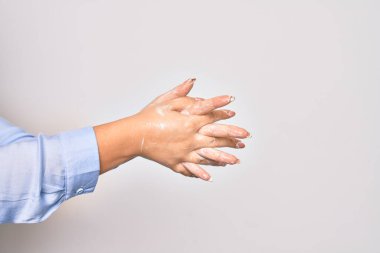 Beyaz arka planda alkol sıvısıyla el temizleyen genç beyaz kadın.