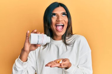 Genç Latin transseksüel kadın elinde haplarla öfkeli ve öfkeli çığlıklar atıyor öfkeyle bağırıyor, öfkeyle yukarı bakıyor.. 