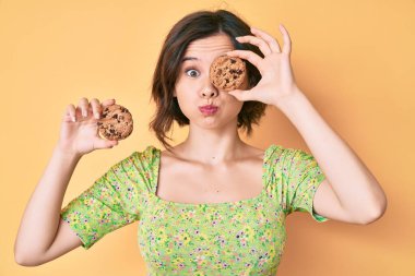 Kurabiye tutan genç ve güzel bir kadın komik suratıyla yanak şişiriyor. Ağzı havayla şişer, havayı yakalar.. 