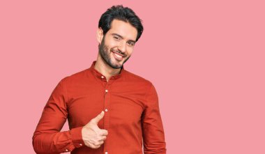 Gündelik kıyafetler giyen genç İspanyol adam elleriyle mutlu bir jest yapıyor. Kameraya bakıp başarıyı gösteren ifade. 