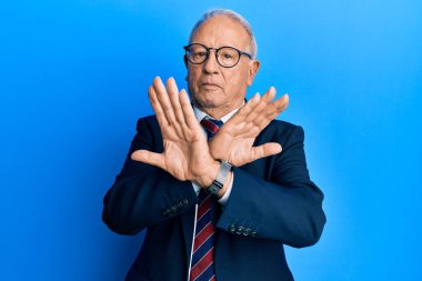 Beyaz üst düzey bir adam iş elbisesi ve kravat reddi ifadesi takıyor. Kollarını kavuşturuyor ve avuç içleri negatif işaretlerle dolu, kızgın bir yüz. 