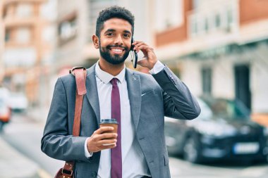 Genç Afrikalı Amerikalı iş adamı akıllı telefondan konuşuyor ve şehirde kahve içiyor..