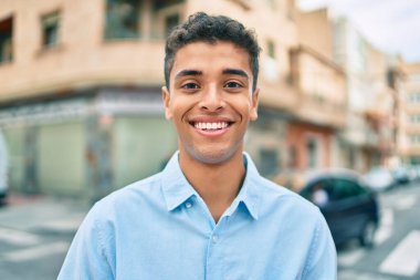 Genç Latin adam gülümseyerek şehirde mutlu mesut yürüyor..