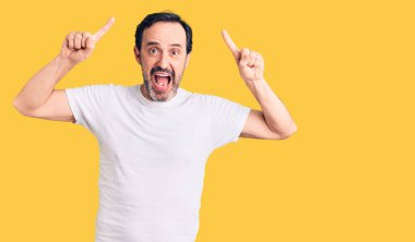 Orta yaşlı, sıradan tişörtler giyen yakışıklı bir adam. Şaşırmış, şaşırmış, parmaklarıyla işaret ediyor ve kollarını kaldırıyordu.. 