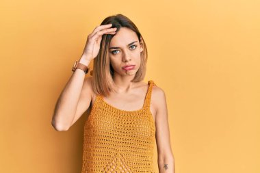 Sıradan sarı tişört giyen beyaz, genç bir kadın. Alnındaki sorun yüzünden endişeli ve stresli. Kriz konusunda endişeli. 