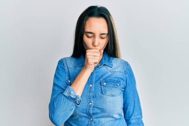 Günlük kot ceket giyen genç İspanyol kadın kendini kötü hissediyor ve soğuk algınlığı veya bronşitin belirtisi olarak öksürüyor. sağlık hizmeti kavramı. 