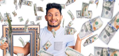 Yakışıklı Latin Amerikalı genç adam boş bir çerçeve tutuyor zaferi mutlu bir gülümsemeyle kutluyor ve kazanan el kaldırarak ifade ediyor