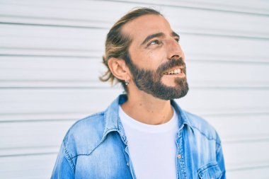 Orta Doğulu genç adam gülümsüyor, mutlu bir şekilde şehirde yürüyor..